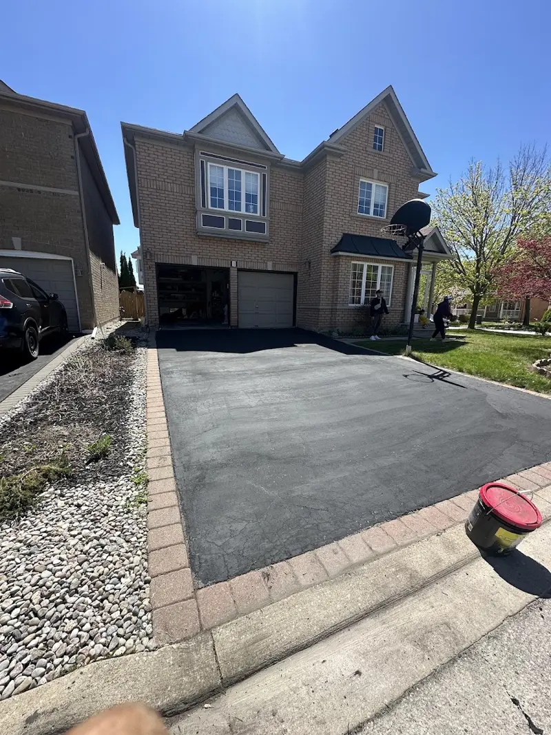 Freshly sealed black asphalt driveway with interlock border